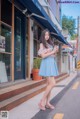 A woman standing on the side of a street holding a cell phone.