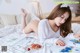 A woman laying on a bed with a plate of fruit.