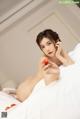 A naked woman laying on a bed holding a strawberry.