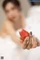 A woman holding a strawberry in her hand.