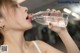 A woman drinking water from a bottle in a gym.