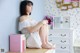 A woman sitting on top of a dresser next to a book.