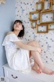 A woman sitting on top of a white dresser.