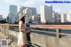 A woman in a white dress and hat standing on a bridge.