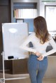 A woman standing in front of a white board with writing on it.