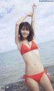 A woman in a red bikini standing on a beach.