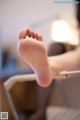 A woman's bare feet on a chair in a room.