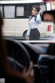 A woman in a blue shirt and black skirt talking on a cell phone.