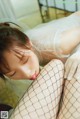 A woman in a white dress and fishnet stockings laying on the floor.