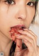 A woman is eating a piece of meat in her mouth.