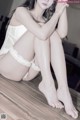 A woman in a white lingerie sitting on a wooden floor.