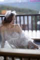 A woman in a white lingerie sitting on a balcony.