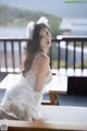 A woman in a white dress sitting on a table.