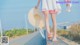 A woman in a white dress and a straw hat walking down a road.