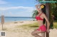 A woman in a red bikini posing on a beach.