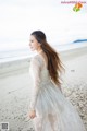 A woman in a white dress standing on a beach.