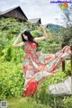 A woman in a long red dress standing on a wooden bridge.