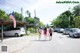 A group of people walking down a street next to parked cars.