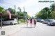 A group of people walking down a street next to parked cars.