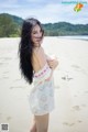 A woman in a white dress standing on a beach.