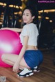 A woman sitting on a pink ball in a gym.