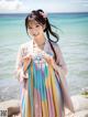 A woman in a colorful dress standing on a beach.