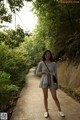 A woman standing on a sidewalk in a park.