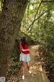 A woman standing next to a tree in a forest.