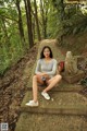 A woman sitting on the steps of a stone path in the woods.