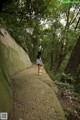 A woman walking down a path in the woods.