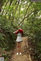 A woman in a gray dress standing on a path in the woods.