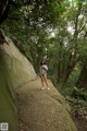 A naked woman walking down a path in the woods.