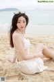 A woman in a white bikini sitting on the beach.