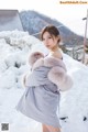 A woman standing in the snow wearing a fur coat.