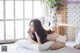 A woman laying on top of a bed next to a window.