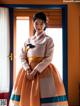 A woman in a korean dress standing in front of a window.