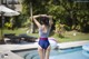 A woman in a bathing suit standing by a swimming pool.