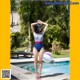 A woman in a bathing suit standing next to a swimming pool.