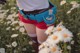 A woman in a field of daisies holding a bottle of water.