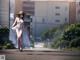 A woman in a white dress and hat walking down a street.