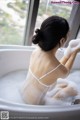 A woman taking a bath in a bathtub with foam.