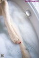 A woman's legs in a bathtub filled with foam.