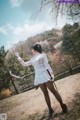 A woman in a white dress holding a sword in a park.