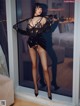 A woman in a black lingerie posing in front of a window.