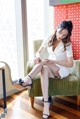 A woman sitting on a green chair with her legs crossed.