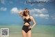 A woman in a black bathing suit standing on the beach.