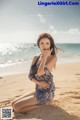 A woman sitting on a sandy beach next to the ocean.