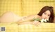 A woman laying on a yellow couch holding a flower.