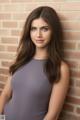 A woman in a gray dress leaning against a brick wall.