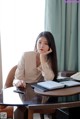 A woman sitting at a table with her hand on her chin.